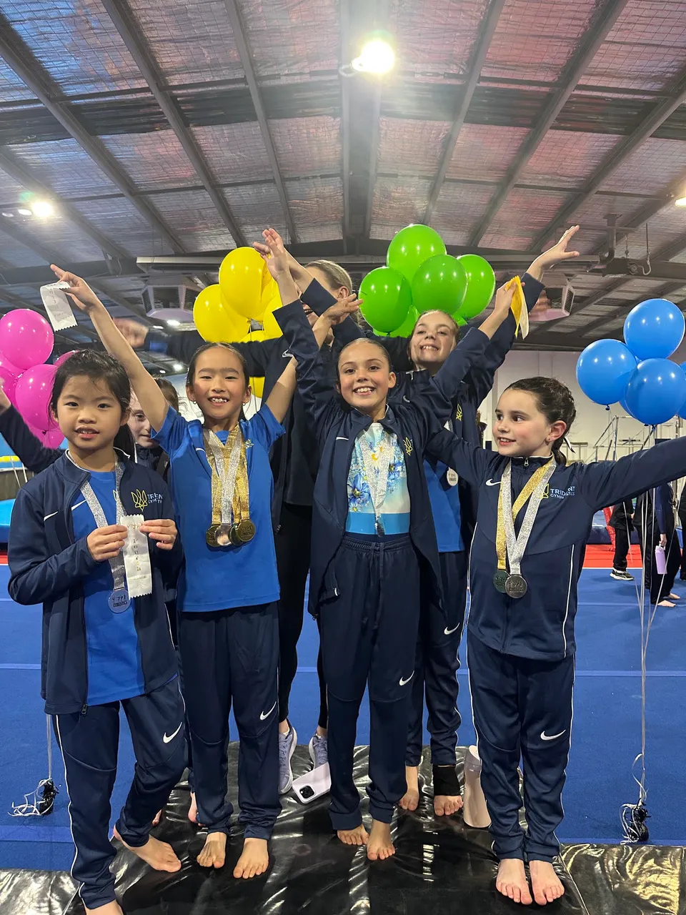 Trident squad gymnasts celebrating together with their medals and ribbons